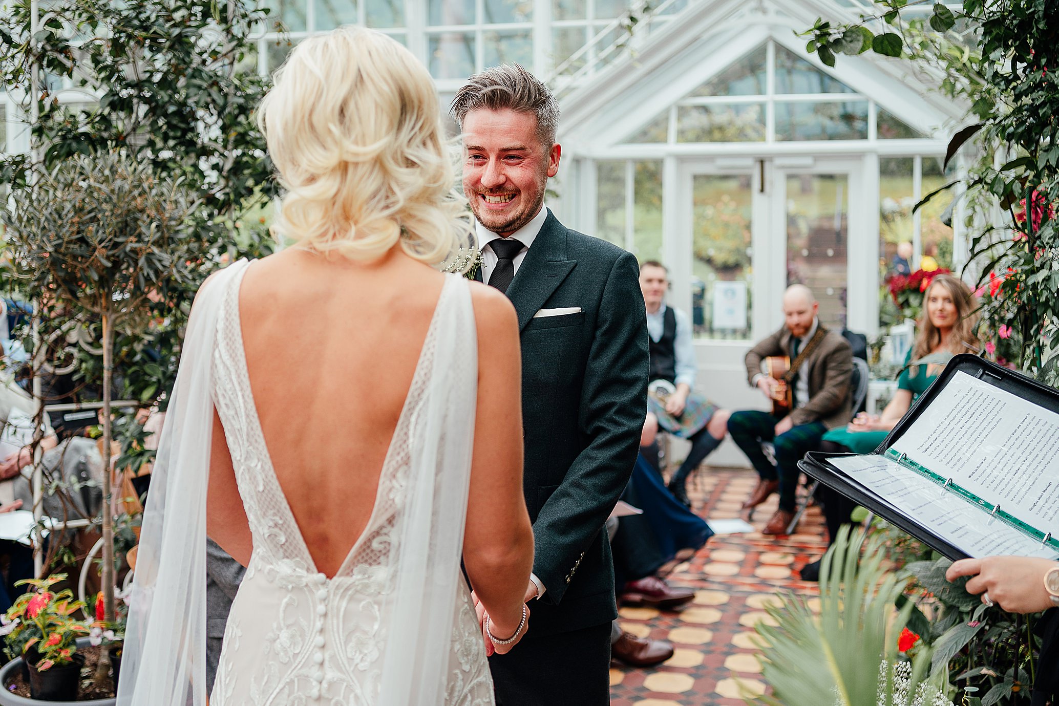 groom with huge smile seeing bride in beautiful white dress for first time at wedding ceremonty in glasshouse surrounded by plants belleisle conservatory glasshouse wedding fotomaki photography