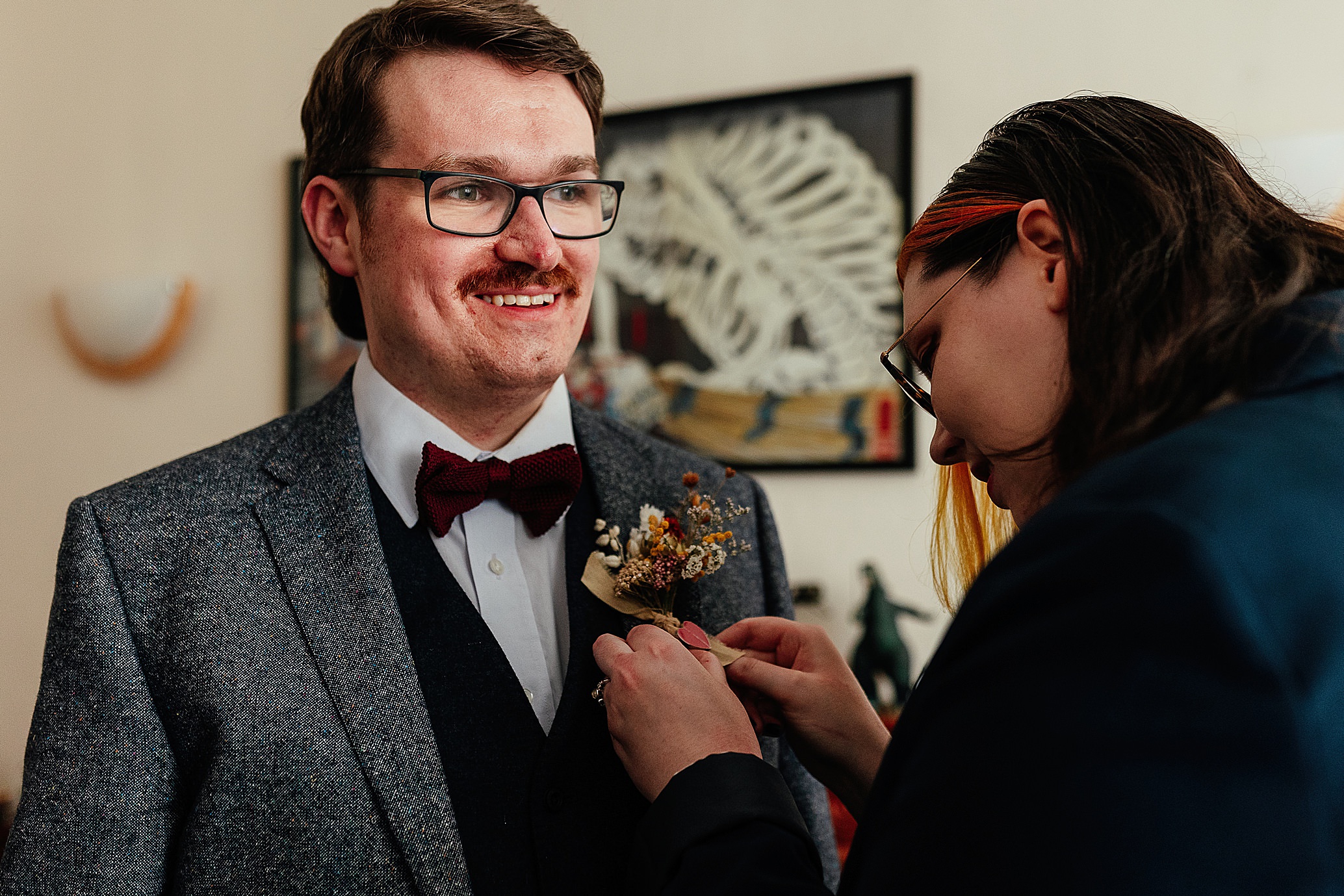 groom wearing grey tweed jacket having floral buttonhole pinned on jacket pollokshields burgh hall wedding glasgow