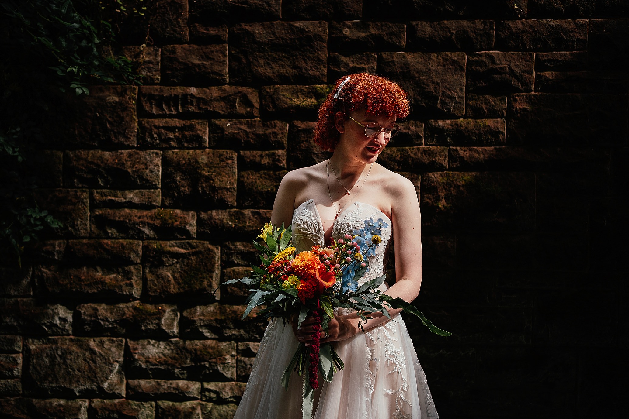 ginger bride wearing white dress holding bouquet in front of wall alternative pollokshields burgh hall wedding