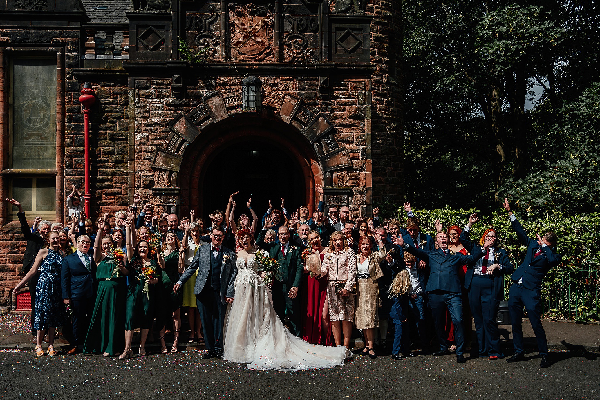 group shot of all wedding guests with hand in the air natural pollokshields burgh hall wedding scotland