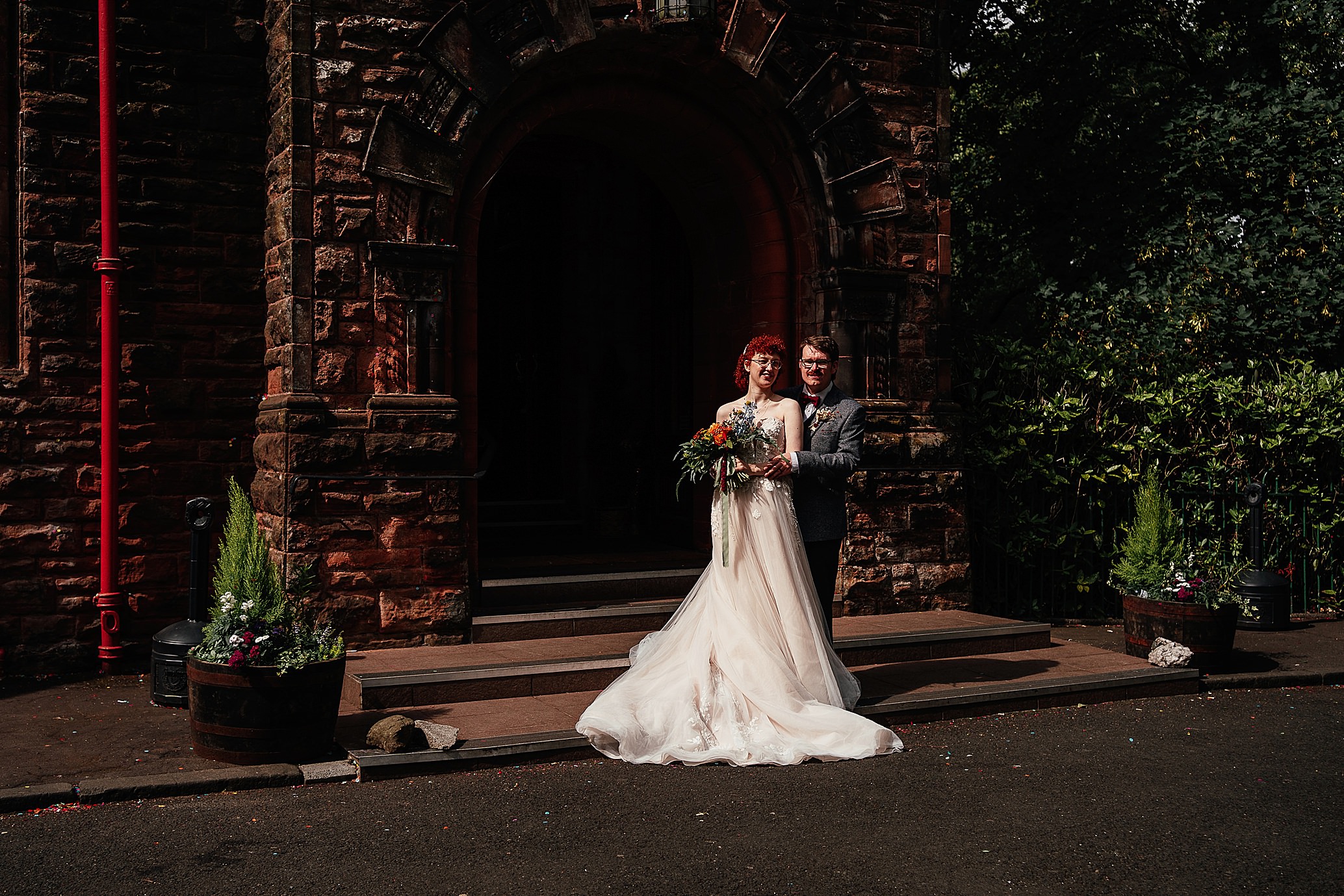 groom holds bride from behind at hall entrance pollokshields burgh hall wedding glasgow scotland