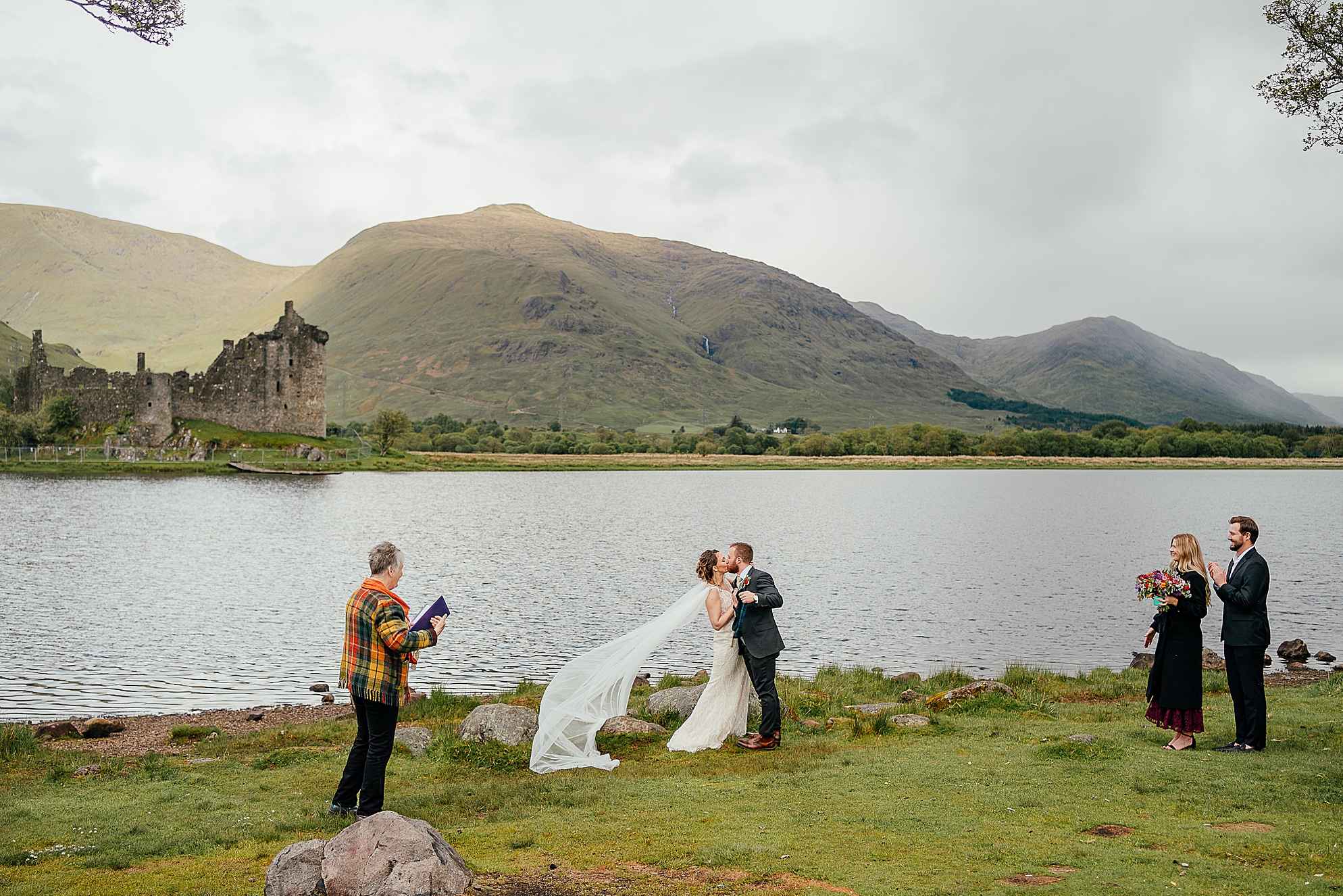 bride and groom kissing during kilchurn castle wedding ceremony or elopement outdoors on loch awe scotland