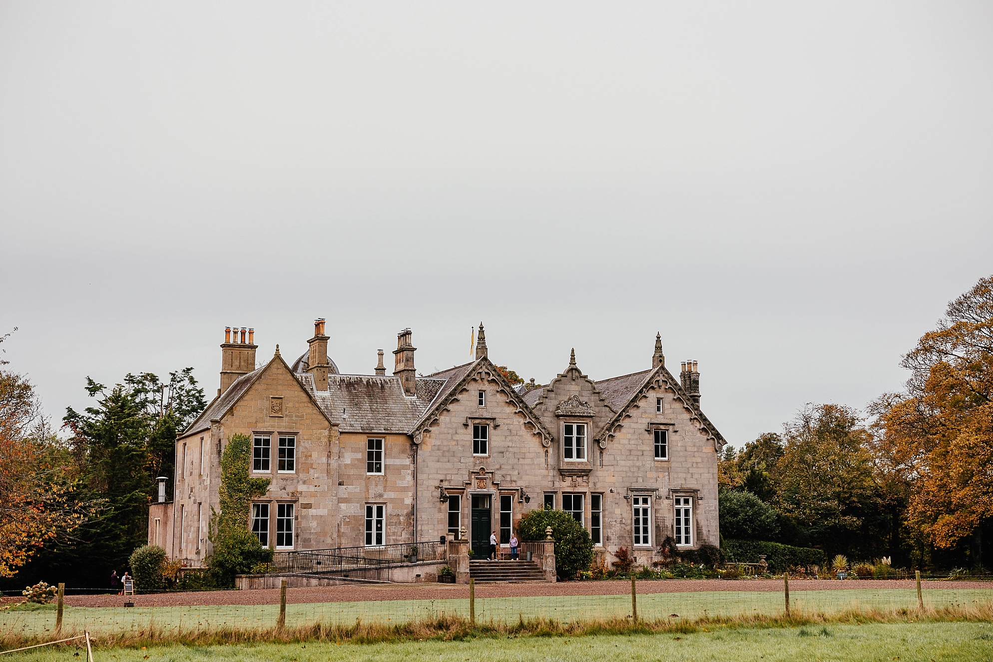 outside exterior view of Netherbyres House wedding in Eyemouth Scotland on an Autumn day a rustic and characterful large Victorian stately home surrounded by mature trees and lawn in a red gravel courtyard