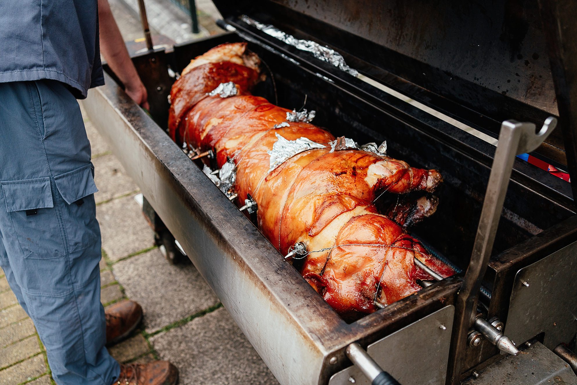 outside exterior view of Netherbyres House wedding venue in Eyemouth Scotland a whole pig is roasted on a spit in an outdoor area of the grounds