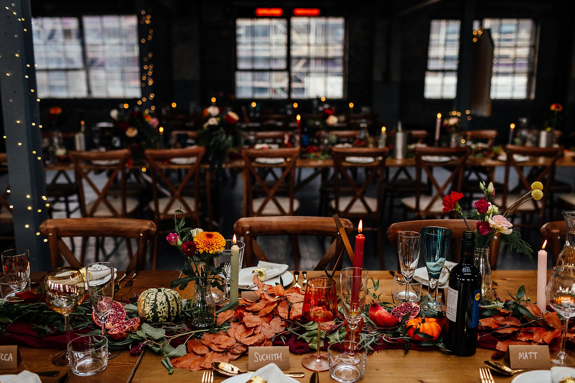 interior of the biscuit factory edinburgh set up for a wedding reception with green, red and yellow autumn touches on the table decorations