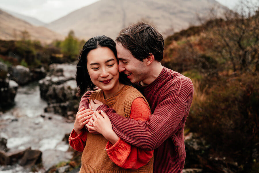 a couple embrace in the rain in glencoe on a photoshoot