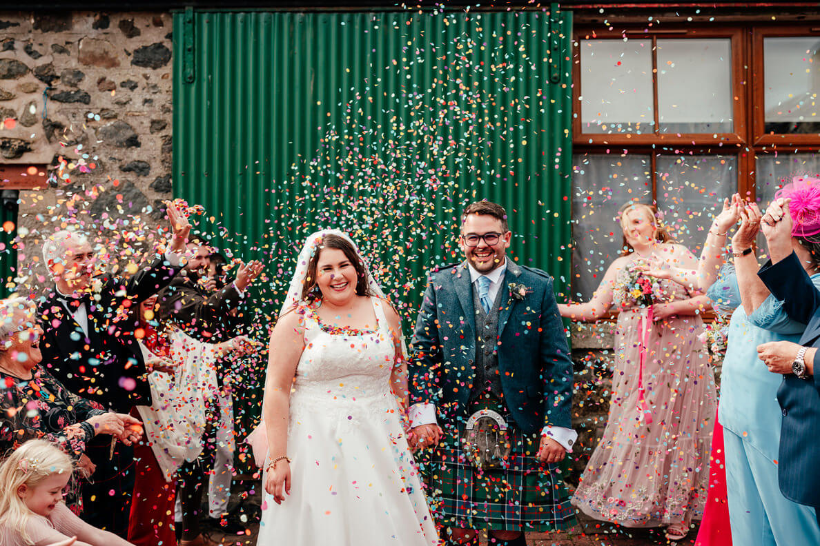 bride and groom in a swirl of colourful confetti at their glasgow wedding