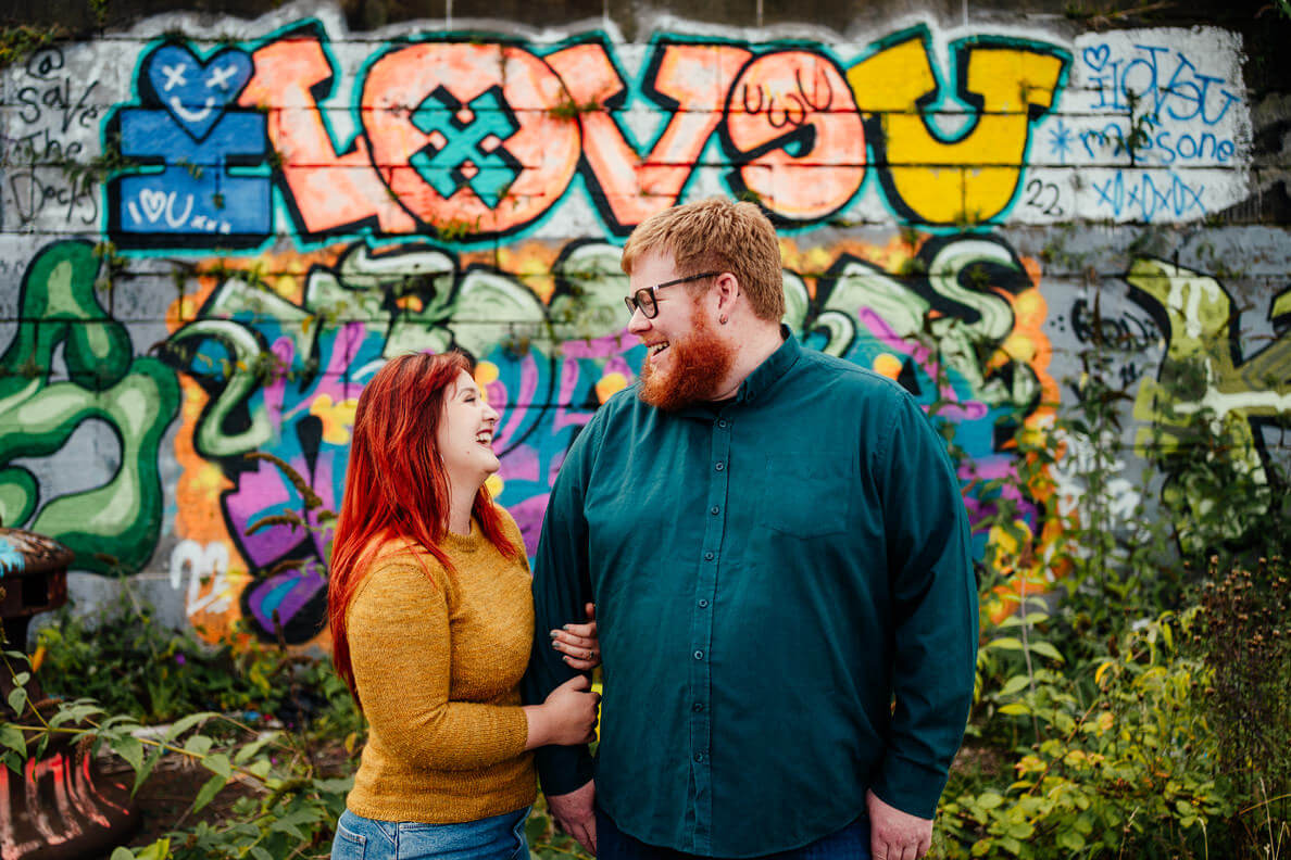 couple on their pre wedding engagement shoot in front of colourful graffiti in glasgow